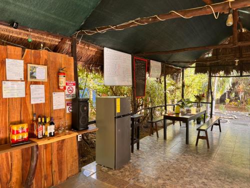 a bar with a refrigerator and a table and chairs at Sabalo Lodge Tours and Cabins in Sierpe