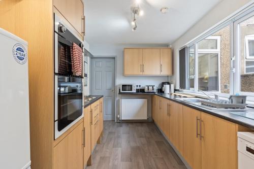 a large kitchen with wooden cabinets and appliances at Spacious 3BR House -Sleeps 7 - Contractor Friendly in Grimsby