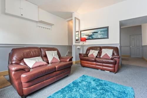 a living room with two leather couches and a blue rug at Spacious 3BR House -Sleeps 7 - Contractor Friendly in Grimsby