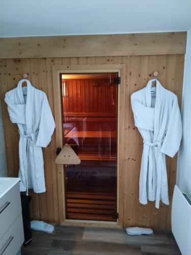 a bathroom with white robes hanging on a wall at Les Terrasses de Besançon in Besançon