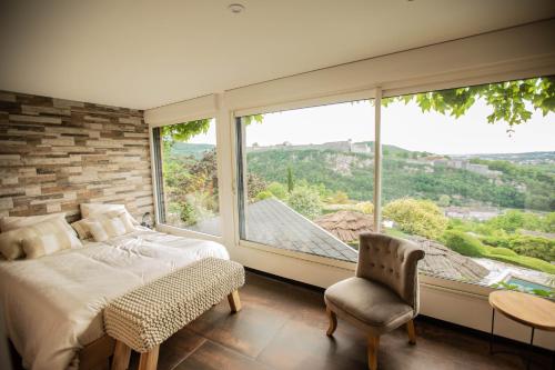 a bedroom with a large window and a bed and a chair at Les Terrasses de Besançon in Besançon
