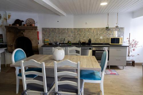 a kitchen with a wooden table and blue chairs at Casa do Balcão in Meda