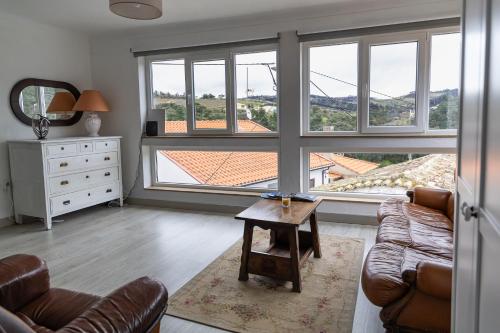 a living room with a couch and a table and windows at Casa do Balcão in Meda