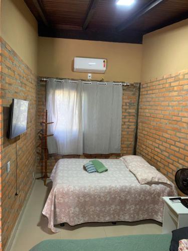 a bedroom with a bed and a brick wall at Casa Studio Uirá em Chapada dos Guimarães in Chapada dos Guimarães