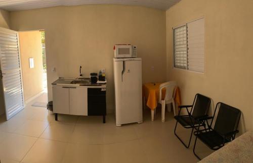 a kitchen with a refrigerator and a table and chairs at Casa Studio Uirá - rua dos Cravos in Chapada dos Guimarães