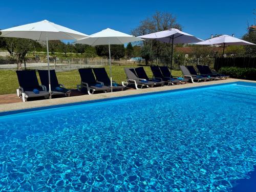 a group of chairs and umbrellas next to a swimming pool at 6 bedroom countryhouse with pool - Casa do Sepião in Vinhal