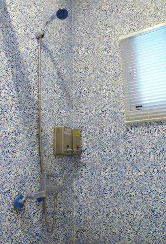 une douche dans une salle de bain avec lumière et fenêtre dans l'établissement Knock Knock Hostel, à Kaohsiung