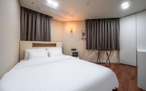 a bedroom with a large white bed and curtains at Regen Hotel in Seoul