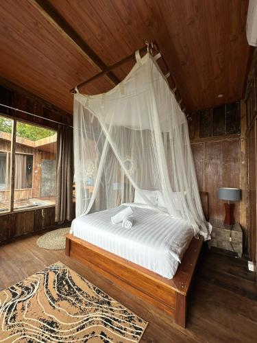 a bedroom with a bed with a mosquito net at Panoramic Samplik View Sidemen in Silebeng