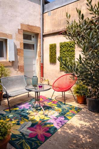 a patio with a table and chairs on a colorful rug at Appartement Oiseau du Paradis avec terrasse parking privé proche centre in Moulins