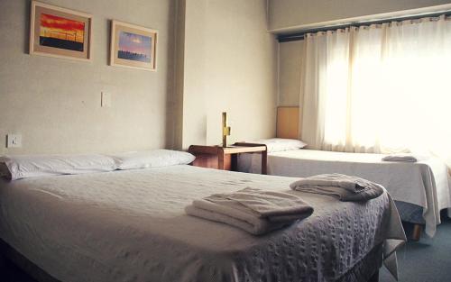 two beds in a hotel room with towels on them at Hotel City in Trelew