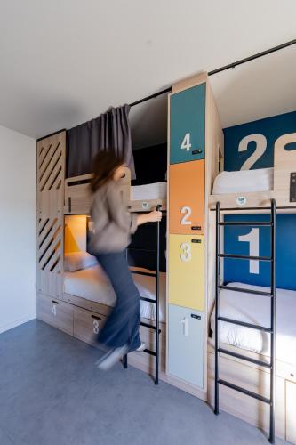 a woman jumping in a room with two bunk beds at SLO HOSTEL Bordeaux in Bordeaux