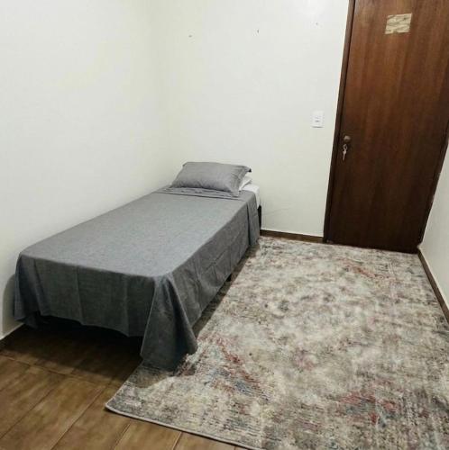 a bedroom with a bed and a rug and a door at Quarto Individual - Centro Rio Verde in Rio Verde