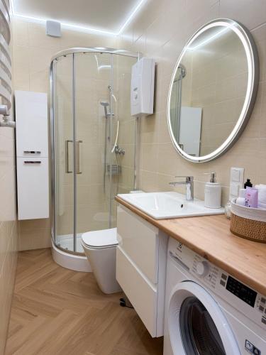 a bathroom with a shower sink and a washing machine at Jaśminowy Apartament in Sławno