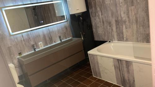a bathroom with a tub and a sink and a mirror at Résidence Bayard in Dinant