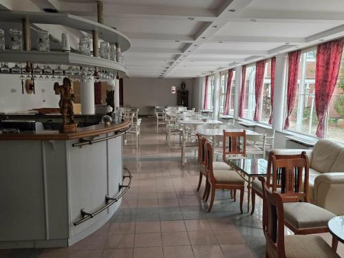 a dining room with tables and chairs and windows at Négy Évszak Panziò in Siófok