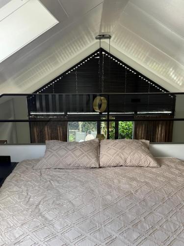 a bedroom with a large bed in front of a window at Cozy & Modern Tiny House in Velserbroek 