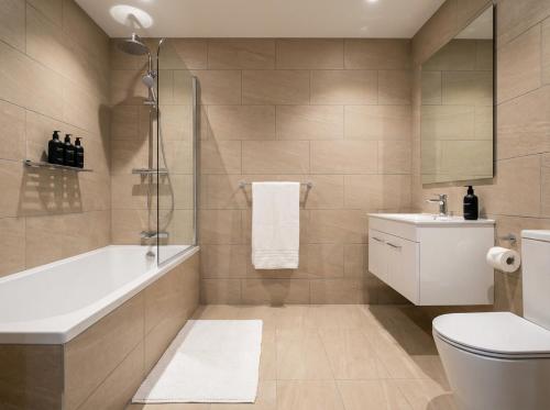 a bathroom with a tub and a toilet and a sink at 2 Bed Liverpool Street Loft in London