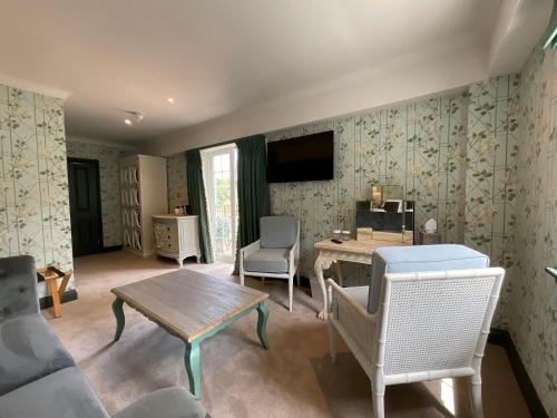 a living room with a table and chairs and a tv at Moorhill House Hotel in Burley