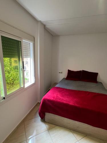 a bedroom with a red bed and a window at Apparemment BAHRA in Taza