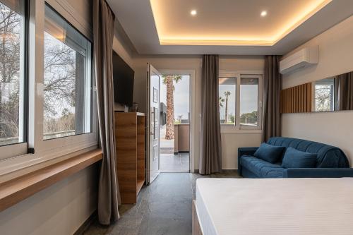 a room with a bed and a couch and windows at OLYMPIADA GIRNI Suites in Paralia Katerinis