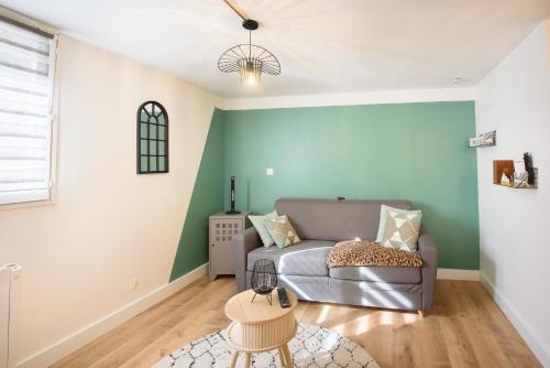 a living room with a gray couch and a green wall at Studio tout confort proche des thermes in Vals-les-Bains