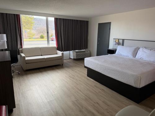 a hotel room with a bed and a chair at Ramada by Wyndham Cobleskill in Cobleskill