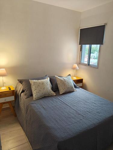 a bedroom with a bed with pillows and a window at Balcón de Lourdes in Santos Lugares