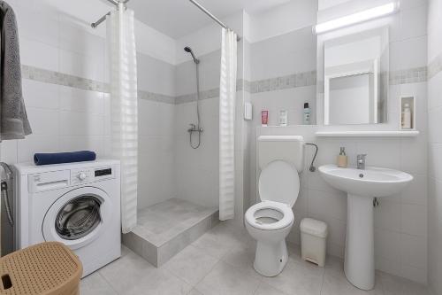 a white bathroom with a washing machine and a sink at Nicolle Elite Apartment in Piteşti