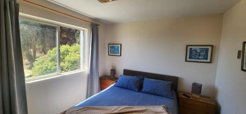 a bedroom with a blue bed and a window at Departamento en Playa Las Cadenas in Algarrobo