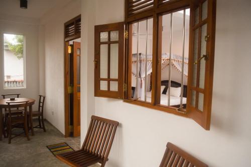 a room with a table and chairs and windows at Villa Mihindi in Hikkaduwa