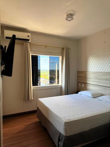 a bedroom with a large bed and a window at Santa Mônica Palace Hotel in Corumbá