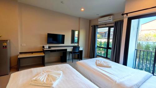 a bedroom with two beds and a desk with a computer at Prajan Residence in Buriram