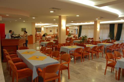 a restaurant with white tables and orange chairs and a counter at Hotel Makpetrol Struga in Struga