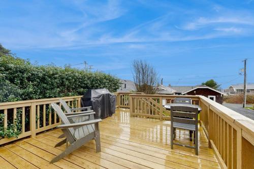 a wooden deck with two chairs and a grill on it at Dog-friendly comfy cabin only two blocks from the beach in Cannon Beach