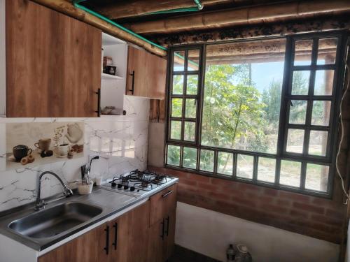 a kitchen with a sink and a stove and a window at Salon de eventos cabaña el Chalet in Paipa