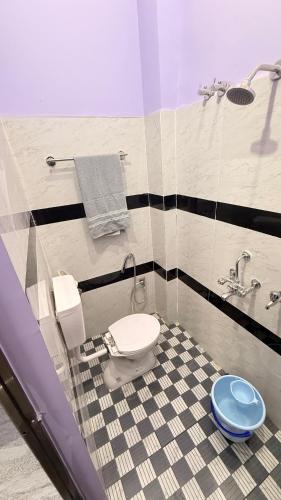 a bathroom with a toilet and a tiled floor at Arctic Inn in Gorakhpur