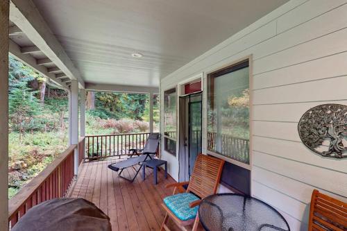 a porch of a house with chairs and tables at Charming riverfront apartment with kitchenette grill & central AC in Welches