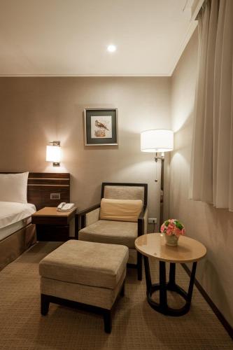 a hotel room with a bed and a chair and a table at SOL Hotel in Hsinchu City