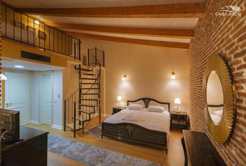 a bedroom with a large bed and a spiral staircase at Casa Gaçe Hotel in Korçë