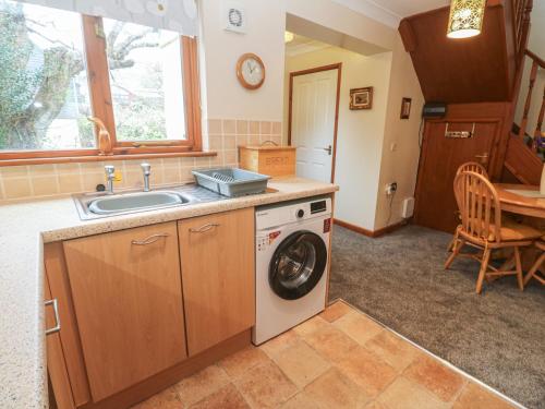 a kitchen with a washing machine and a sink at Two Hoots in Falmouth