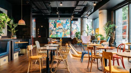 a restaurant with tables and chairs and a large screen at Ruby Zoe Hotel London by IHG in London