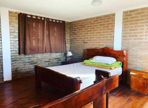 a bedroom with a bed and a brick wall at Complejo Las Carolina in Arroyo de Los Patos