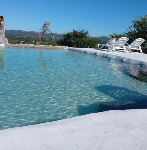a large swimming pool with chairs and water at Complejo Las Carolina in Arroyo de Los Patos