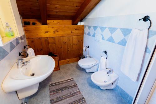 a bathroom with two toilets and a sink and a tub at Chalet Presanella in Temù