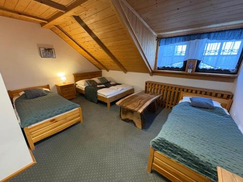 a attic room with two beds and a window at Dolina Rastoki in Koniaków