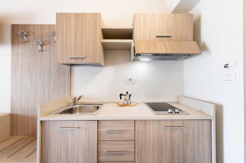 a kitchen with wooden cabinets and a sink at Club del Sole Desenzano Boutique Resort in Desenzano del Garda
