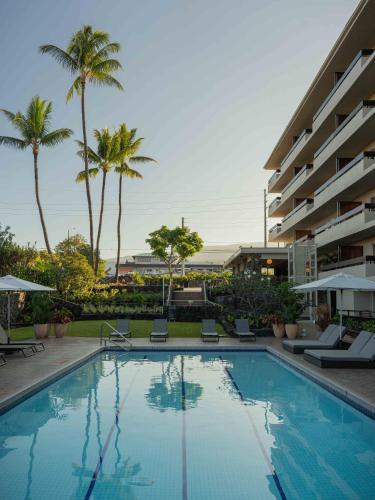 a swimming pool in front of a hotel with palm trees at PACIFIC 19 Kona in Kailua-Kona