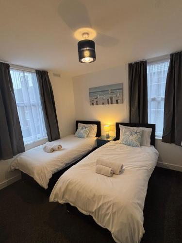 two beds sitting in a room with windows at Seahorse Guesthouse in Great Yarmouth