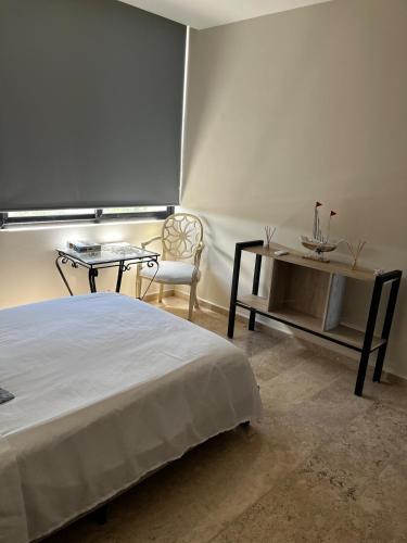 a bedroom with a bed and a table and a chair at Chicxulub , oceanfront 3 recamaras in Chicxulub